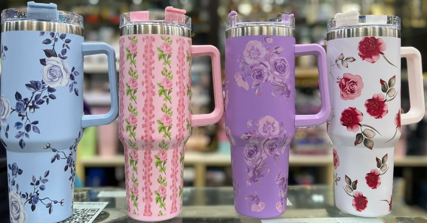 Four floral-patterned tumblers in blue, pink, purple, and white on a blurred background.